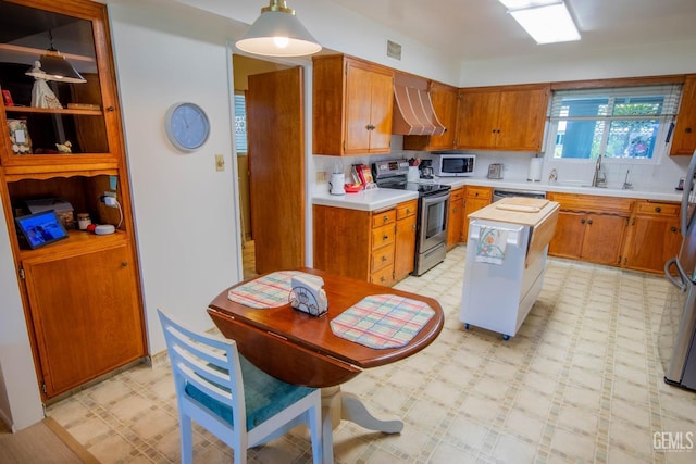 kitchen featuring light floors, light countertops, appliances with stainless steel finishes, wall chimney exhaust hood, and a center island