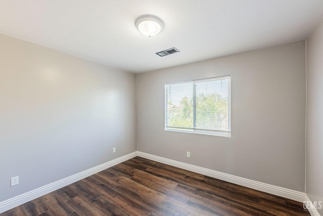 spare room featuring baseboards, visible vents, and dark wood-style flooring