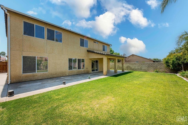 back of house featuring a yard, fence, stucco siding, and a patio