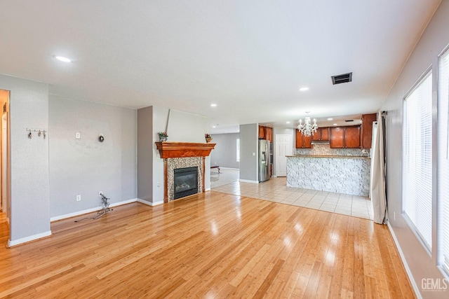 unfurnished living room with baseboards, a fireplace, light wood-style flooring, and a healthy amount of sunlight