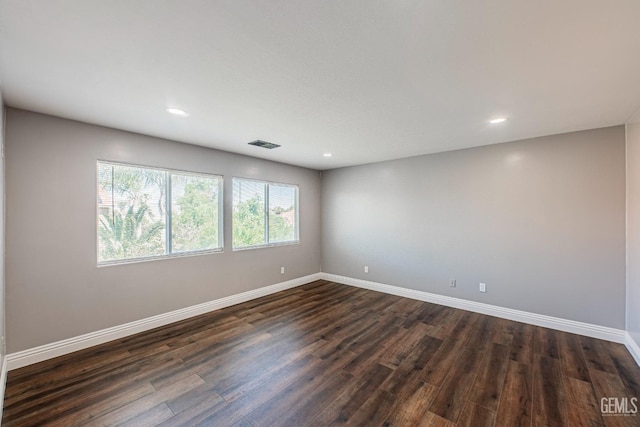 empty room with recessed lighting, visible vents, dark wood finished floors, and baseboards