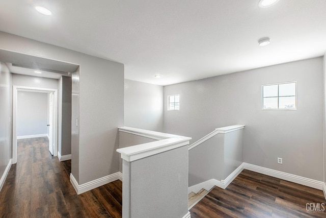 hallway with baseboards, wood finished floors, and an upstairs landing