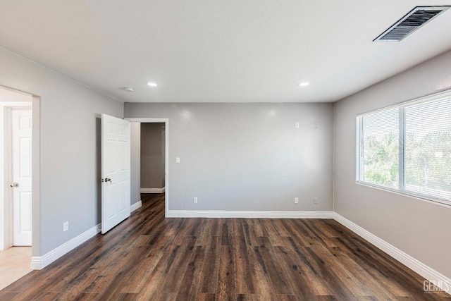 unfurnished room with dark wood-style flooring, recessed lighting, visible vents, and baseboards