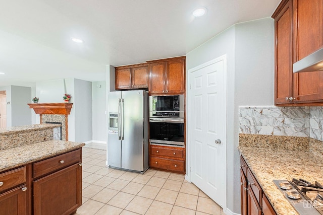 kitchen with light stone counters, brown cabinets, stainless steel appliances, tasteful backsplash, and light tile patterned flooring