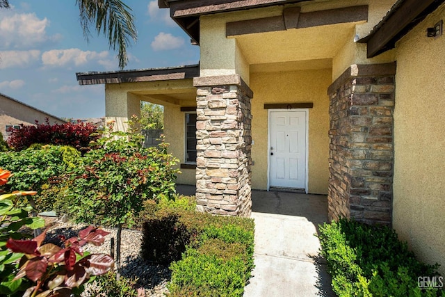 doorway to property featuring stone siding and stucco siding