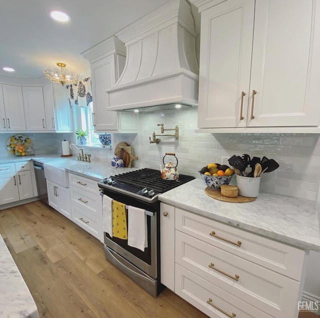 2527 Pine St, Bakersfield, CA 93301 - kitchen featuring stainless steel appliances, custom range hood, light wood finished floors, white cabinets, and a sink