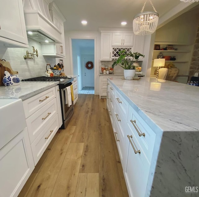 2527 Pine St, Bakersfield, CA 93301 - kitchen with stainless steel range with gas cooktop, custom range hood, white cabinets, light stone countertops, and decorative backsplash