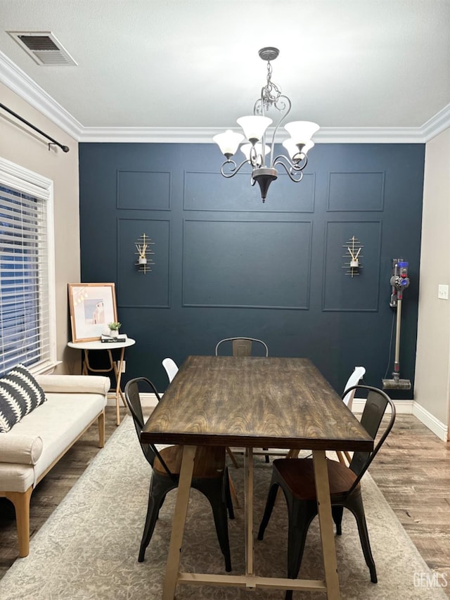 dining space featuring crown molding, wood-type flooring, and a notable chandelier