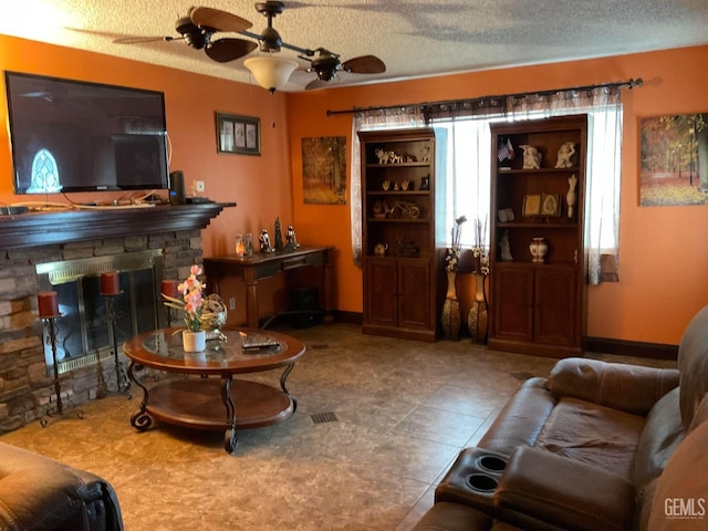 living room with a fireplace, a textured ceiling, and ceiling fan