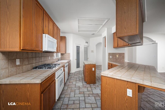 6307 San Rogue Ct, Bakersfield, CA 93312 - kitchen featuring white appliances, a peninsula, arched walkways, a sink, and backsplash