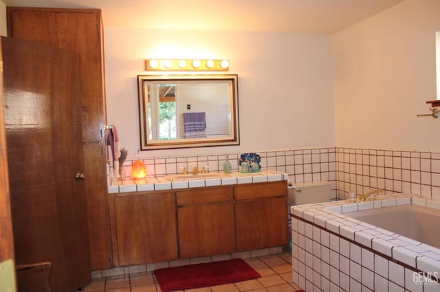 bathroom with tile patterned flooring, vanity, and tiled bath