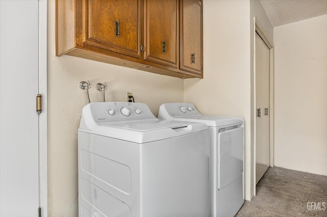 clothes washing area with a textured ceiling, separate washer and dryer, and cabinet space