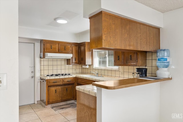 kitchen with light countertops, brown cabinetry, and a peninsula