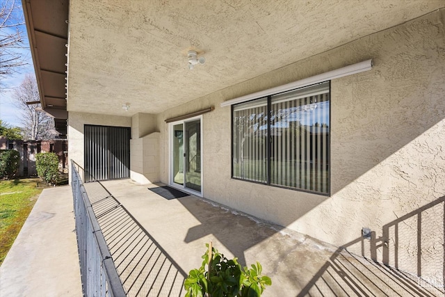 view of exterior entry featuring a patio, fence, and stucco siding