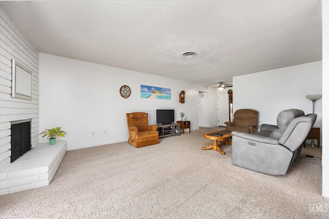 carpeted living area with a brick fireplace, a ceiling fan, visible vents, and a textured ceiling