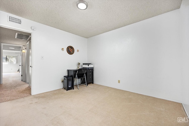 office space with a textured ceiling, carpet flooring, and visible vents