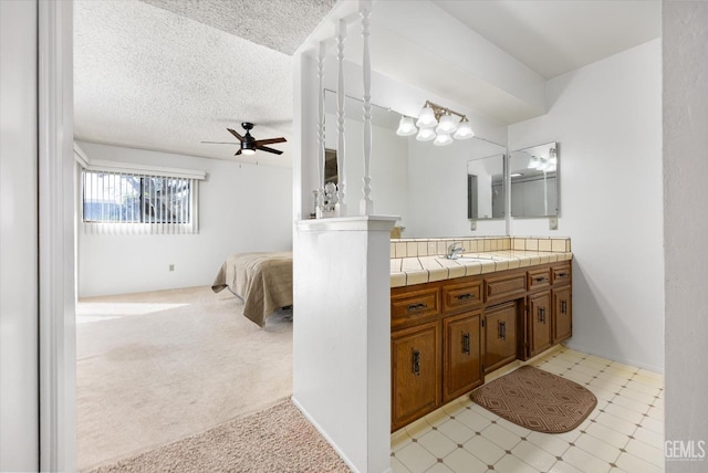 full bath featuring a textured ceiling, connected bathroom, vanity, a ceiling fan, and tile patterned floors