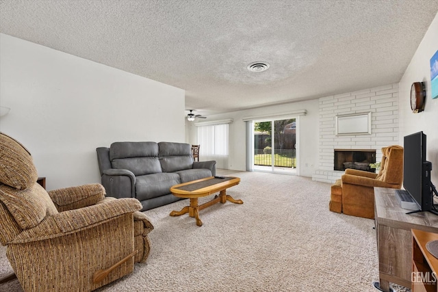 carpeted living area featuring a textured ceiling, a fireplace, visible vents, and a ceiling fan