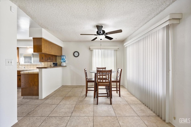 dining area with ceiling fan, a textured ceiling, and light tile patterned floors