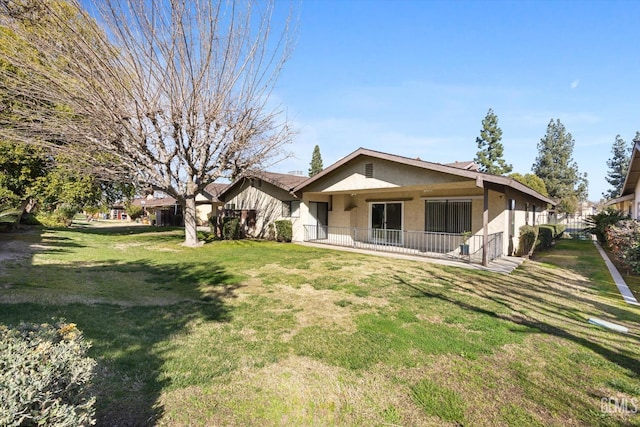 rear view of house with a yard and stucco siding