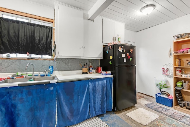 kitchen featuring white cabinetry, sink, beamed ceiling, decorative backsplash, and black refrigerator