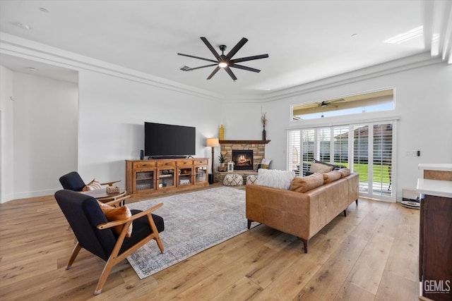 living room with light wood-type flooring, a fireplace, baseboards, and a ceiling fan