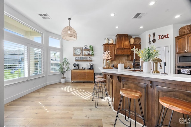 kitchen featuring appliances with stainless steel finishes, a kitchen bar, visible vents, and decorative backsplash