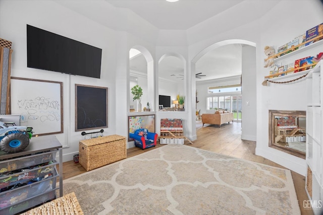 interior space with arched walkways, ceiling fan, baseboards, and wood finished floors