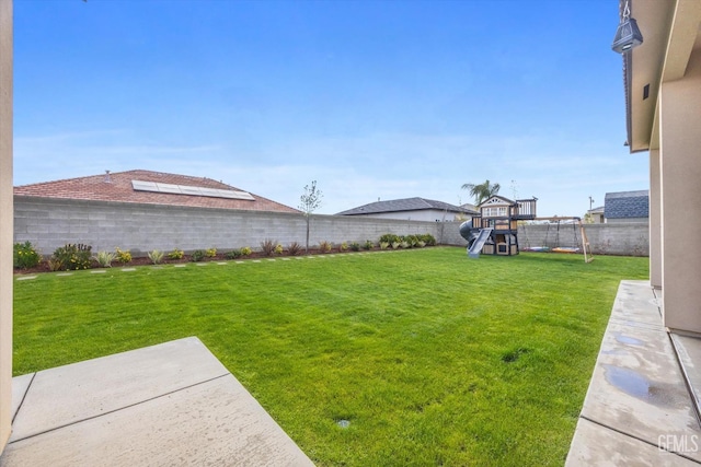 view of yard with a fenced backyard, a playground, and a patio