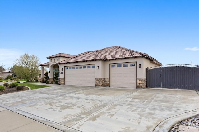 exterior space with stucco siding, concrete driveway, an attached garage, a gate, and stone siding