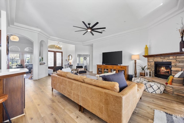 living area featuring a healthy amount of sunlight, light wood-style floors, and a stone fireplace