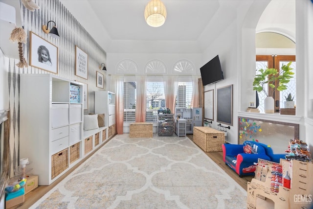 interior space featuring arched walkways, a raised ceiling, french doors, and wood finished floors