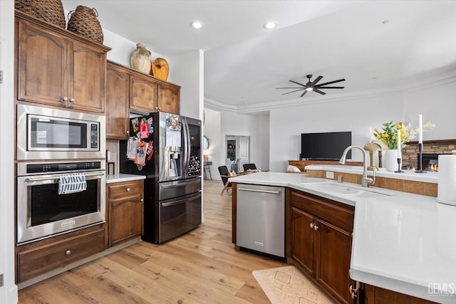 kitchen featuring light wood-style flooring, open floor plan, light countertops, stainless steel appliances, and a sink