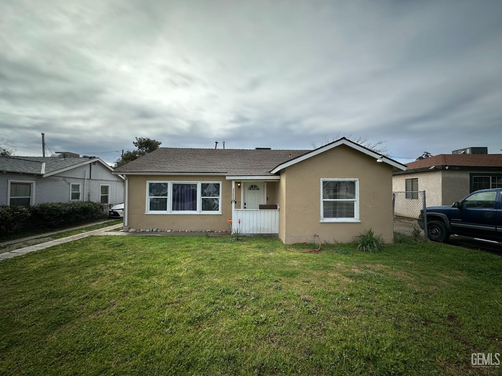 view of front of home featuring stucco siding, a front yard, and fence