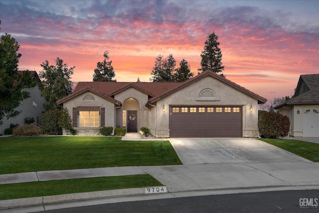 view of front of home with stucco siding, concrete driveway, an attached garage, a front yard, and a tiled roof