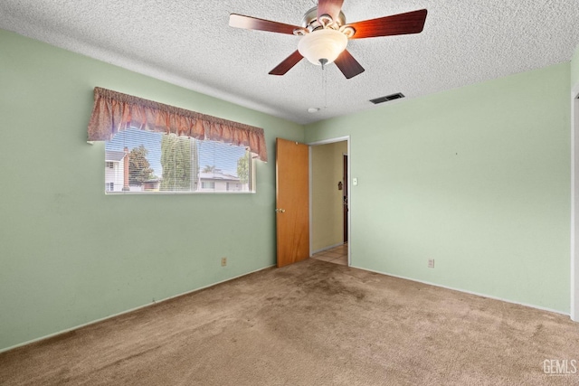 carpeted empty room with a textured ceiling, visible vents, and ceiling fan