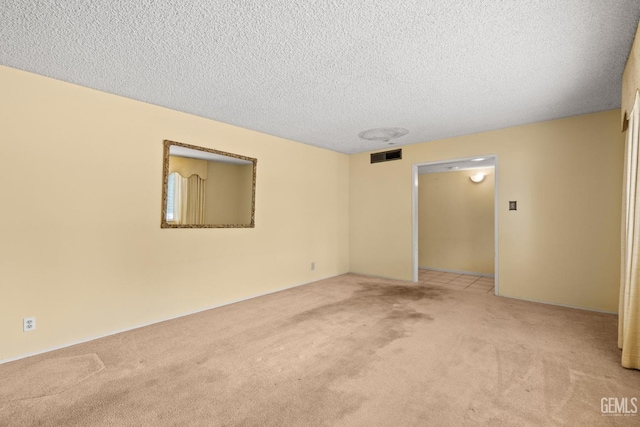 carpeted empty room with a textured ceiling and visible vents