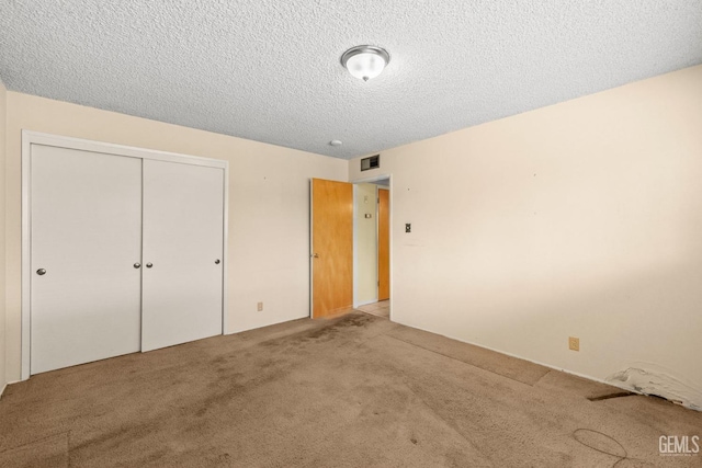 unfurnished bedroom with carpet flooring, a textured ceiling, and a closet