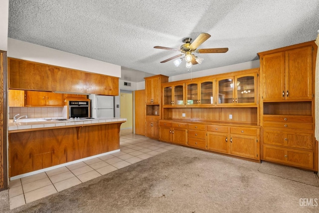 kitchen featuring ceiling fan, brown cabinetry, and white appliances