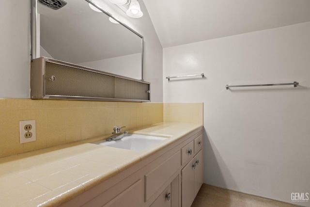 bathroom featuring vanity, tasteful backsplash, and vaulted ceiling