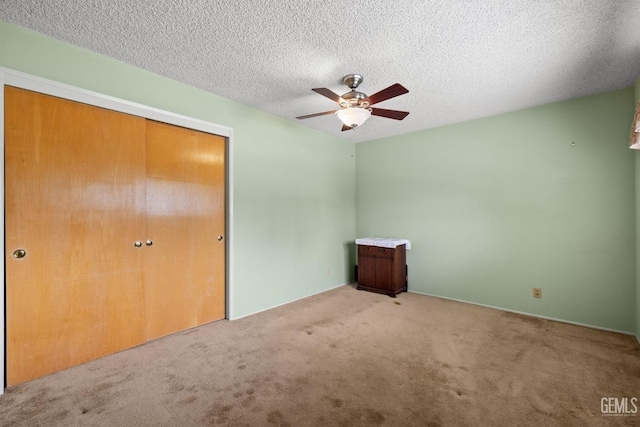 unfurnished bedroom featuring carpet floors, a textured ceiling, ceiling fan, and a closet