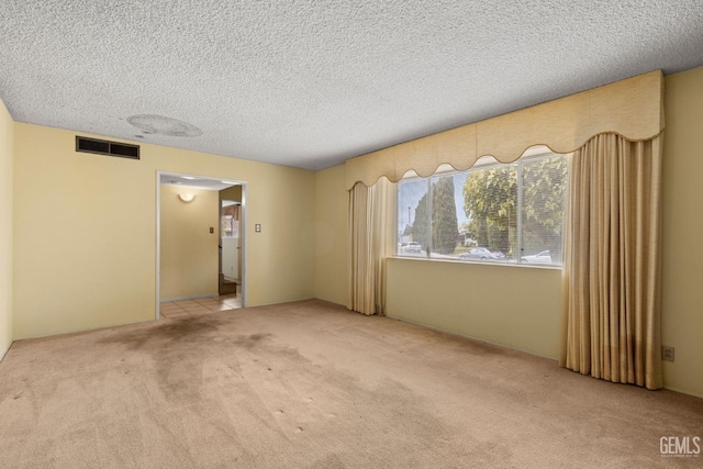 carpeted empty room with visible vents and a textured ceiling