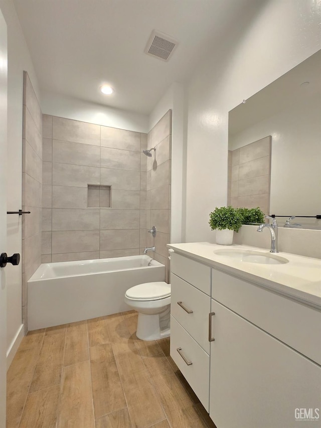 bathroom with visible vents, wood tiled floor, toilet, bathtub / shower combination, and vanity