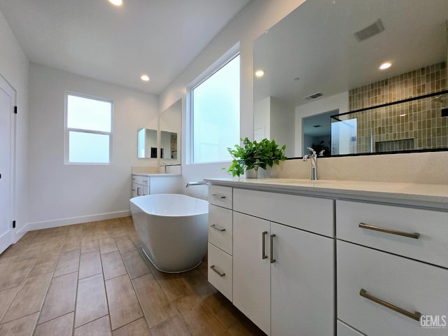 bathroom with visible vents, a freestanding tub, a sink, wood finished floors, and recessed lighting