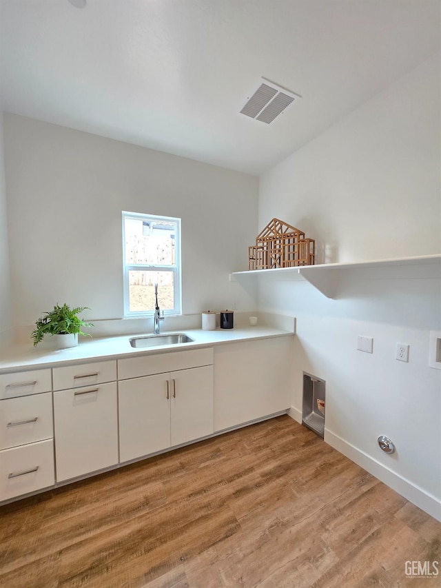 clothes washing area with visible vents, a sink, cabinet space, light wood-style floors, and hookup for a washing machine