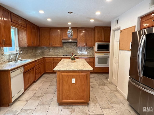 7412 Indian Gulch St, Bakersfield, CA 93313 - kitchen featuring stainless steel appliances, under cabinet range hood, a center island, tasteful backsplash, and brown cabinets
