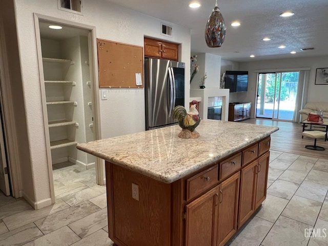 7412 Indian Gulch St, Bakersfield, CA 93313 - kitchen with freestanding refrigerator, brown cabinets, open floor plan, recessed lighting, and a center island