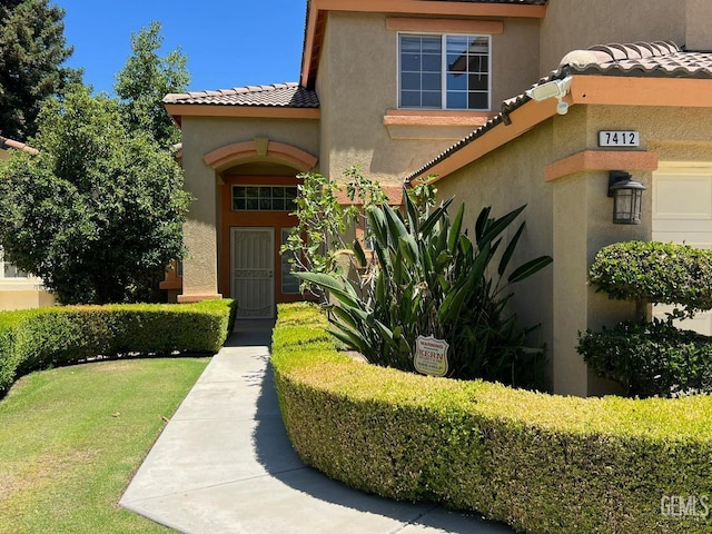 7412 Indian Gulch St, Bakersfield, CA 93313 - entrance to property with a tiled roof, stucco siding, and a lawn