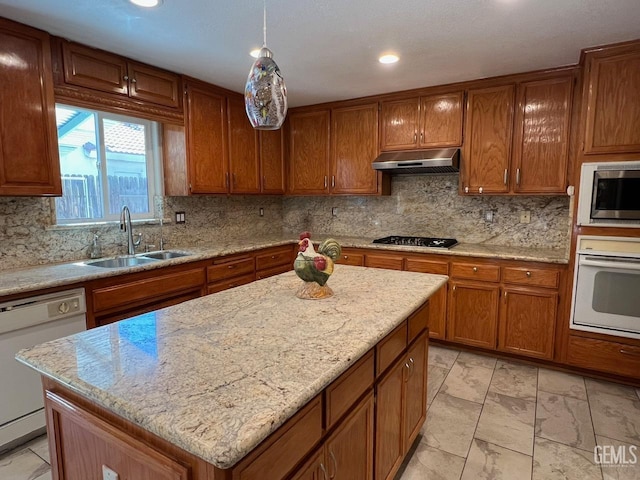 7412 Indian Gulch St, Bakersfield, CA 93313 - kitchen featuring stainless steel appliances, under cabinet range hood, brown cabinets, a kitchen island, and decorative backsplash