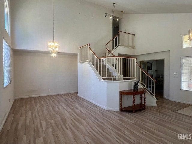 7412 Indian Gulch St, Bakersfield, CA 93313 - unfurnished living room featuring a towering ceiling, wood finished floors, stairway, and a chandelier